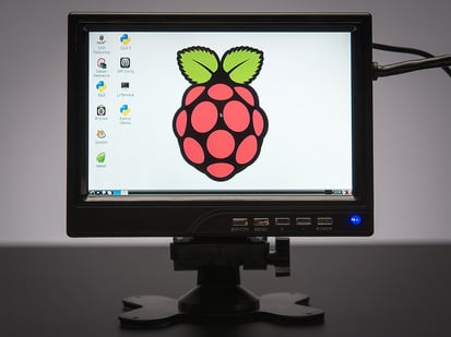 Front view of assembled and powered on HDMI 4 Pi - 7" Display. The monitor displays a desktop background with a raspberry logo.