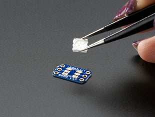 Hand holding 5050 size LED next to breakout board