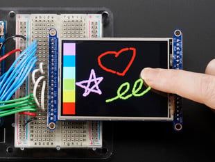 Close Up Demo Shot of the TFT breakout wired to arduino, showing a finger drawing a heart, star, and swirling line using the touchscreen.
