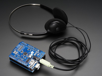 Angled shot of Adafruit "Music Maker" MP3 Shield for Arduino connected to a pair of headphones. 