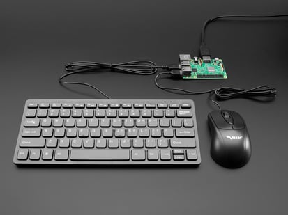 Black keyboard, black optical mouse, and black HDMI cable all connected to green, credit-card-sized microcontroller.