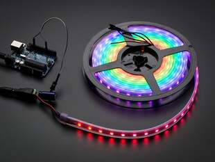 Powered on LED strip on a reel, emitting colored lights.