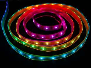 LED strip against black background, emitting rainbow colors.