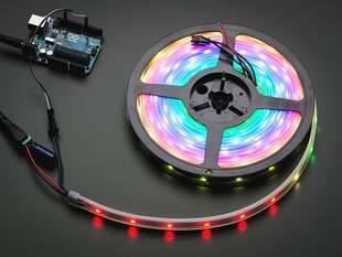 Angled shot of lit RGBW LED strip on a reel.