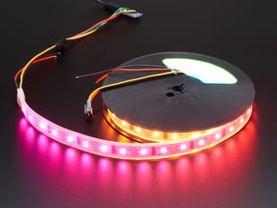 Angled shot of lit RGBW LED strip on a reel.