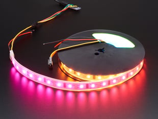 Powered LED strip on a reel emitting pink and red light.