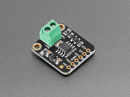 Angled shot of black, square-shaped thermocouple breakout board with a green 2-pin terminal block.