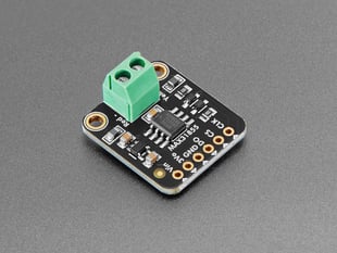 Angled shot of black, square-shaped thermocouple breakout board with a green 2-pin terminal block.