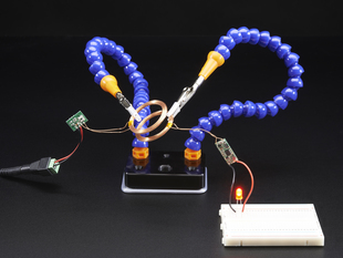 Demo Shot of the Mini Hand from Hobby Creek with Two Arms holding copper rings that are powering a red led.
