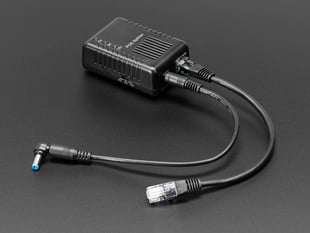 Angled shot of black, rectangle-shaped power over Ethernet splitter with two cables.