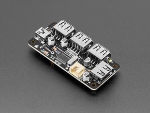 Angled shot of black, rectangular USB hub PCB with four USB-A sockets and one USB Mini-B connector.
