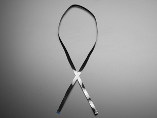 Overhead shot of a black, 100cm long, skinny ribbon cable crossed like a bowtie.