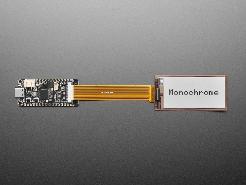 Overhead shot of 2.13" monochrome flexible electronic ink display connected via ribbon cable to a microcontroller. "Monochrome" is in black text.