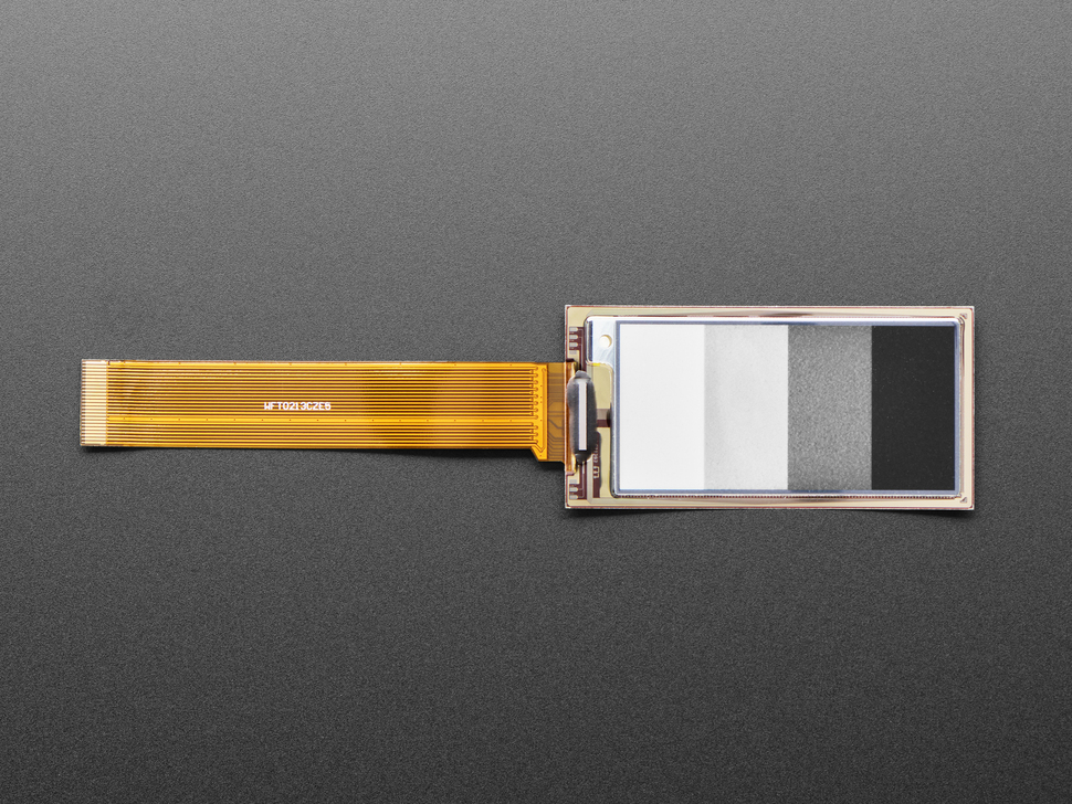 Overhead shot of 2.13" monochrome flexible electronic ink display connected via ribbon cable to a microcontroller. Display is of four blocks in grayscale.