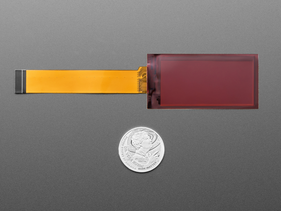 Back of 2.13" flexible electronic ink display with long ribbon cable above U.S. quarter for scale.