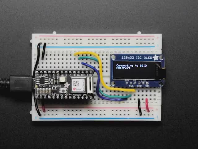 Adafruit AirLift Bitsy Add-On &ndash; ESP32 WiFi Co-Processor connected to a half sized white breadboard and a OLED with various wording showing on the display. 