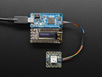 Top view shot of rectangular microcontroller assembled next to an OLED display breakout board can connected to a miniGPS. The OLED displays small white text.