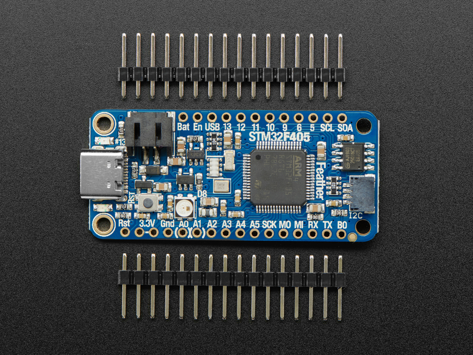 Top view of a blue rectangular microcontroller between two pieces of 16-pin header.