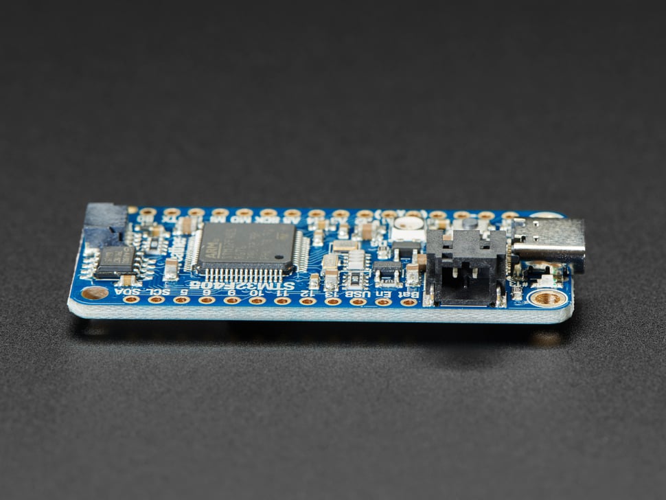 Side detail of STEMMA QT connector on a blue rectangular microcontroller.