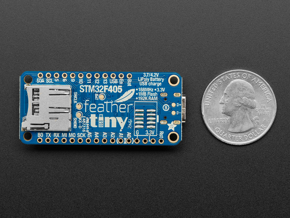 Back of a blue rectangular microcontroller next to US quarter for scale.
