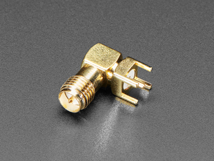Angled shot of small, metallic, right-angle coaxial RF connector.