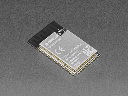 Angled shot of small, black, Wi-Fi module with castellated pads.