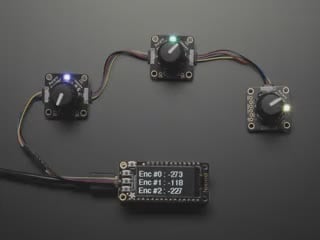 Top view video of a hand turning the rotary encoder knobs on three PCBs. The NeoPixel LEDs on each PCB change color. The OLED display changes its readout data with each twisty-turn.
