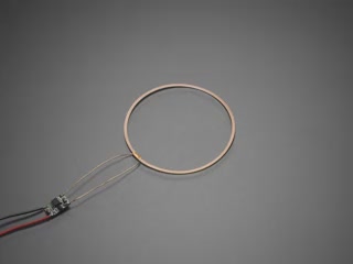Video of a white woman holding ten bare LEDs in her hand. She slides her hand over an inductive charger, lighting up the ten small LEDs.
