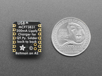 back of small, black, square-shaped breakout board next to US quarter for scale