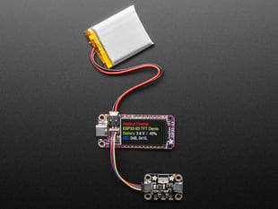 Top view of a purple rectangular microcontroller with a color TFT screen and powered by an ESP32-S3 chip. It is also connected to a Li-Poly battery and a lux sensor breakout. The TFT display reads in colored text: "Adafruit Feather
ESP32-S3 TFT Demo
Battery: 3.8V / 45%
I2C: 0xB, 0x10, "