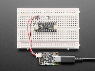 Overhead shot of a half-size breadboard connected to a UPDI board and an AtTiny breakout board. the LEDs light up green on both boards.