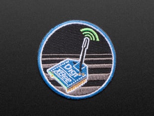 Circular embroidered badge with DIGIXBEE box in blue over a black and grey striped background, with blue trim. 