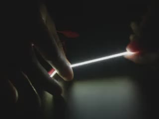 Video of Black hand articulating yellow LED filament.