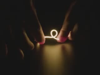 Video of Black hand articulating white LED filament.
