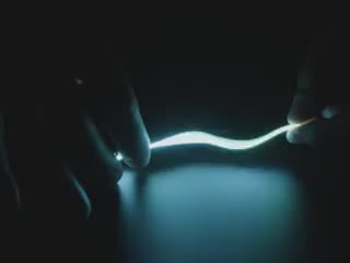 Video of Black hand articulating green LED filament.