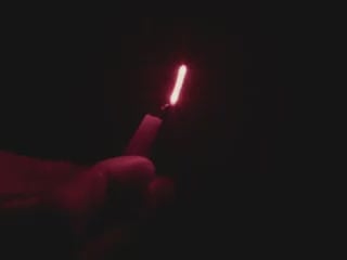 Video of Black hand articulating red LED filament.