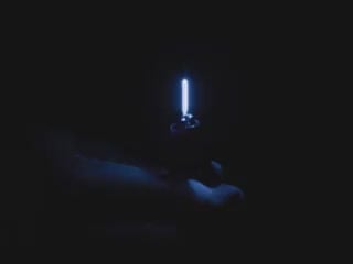 Video of Black hand articulating short blue LED filament.