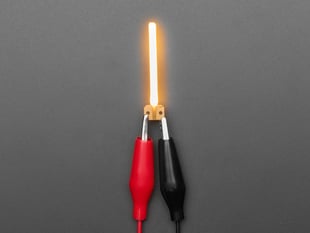 Overhead shot of LED filament in shape of letter "I" lit up with alligator clips.