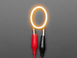 Overhead shot of LED filament in shape of letter "O" lit up with alligator clips.