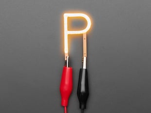 Overhead shot of LED filament in shape of letter "P" lit up with alligator clips.