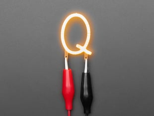 Overhead shot of LED filament in shape of letter "Q" lit up with alligator clips.