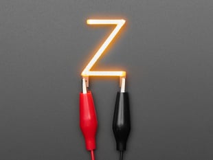 Overhead shot of LED filament in shape of letter "Z" lit up with alligator clips.