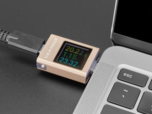 Close-up of square-shaped OLED power meter plugged into a laptop and displaying readout.