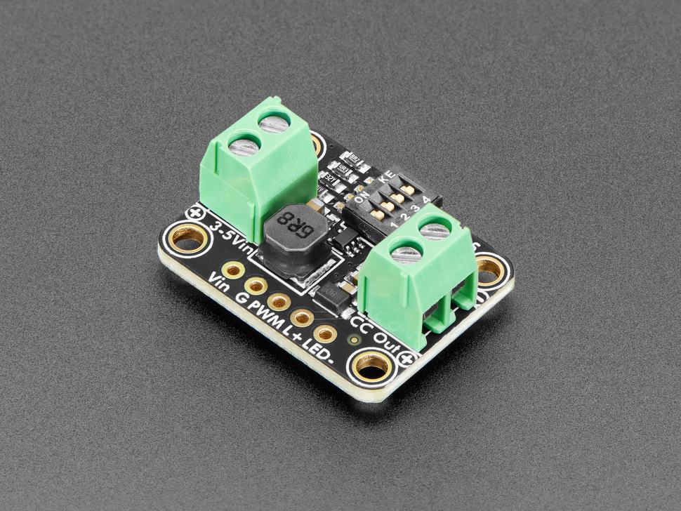 Angled shot of rectangular, black, LED driver board with green terminal blocks.