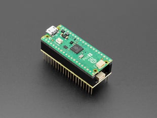 Demo Shot of green rectangular board (Pico 2) attached to the top of the PiCowbell Adalogger.