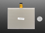 Overhead shot of blank 5.83" monochrome electronic ink display with U.S. quarter for scale.