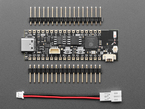 Overhead shot of long, black, skinny, dev board with two pieces of header and a JST-PH adapter cable.