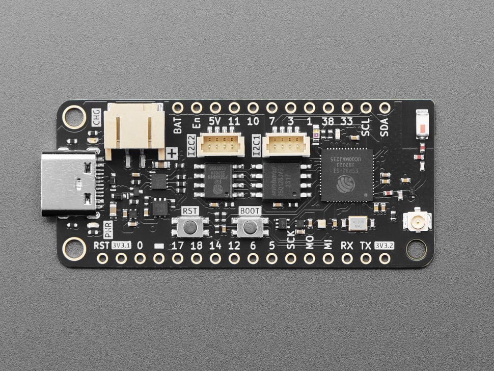 Overhead shot of black, rectangular, Feather microcontroller.