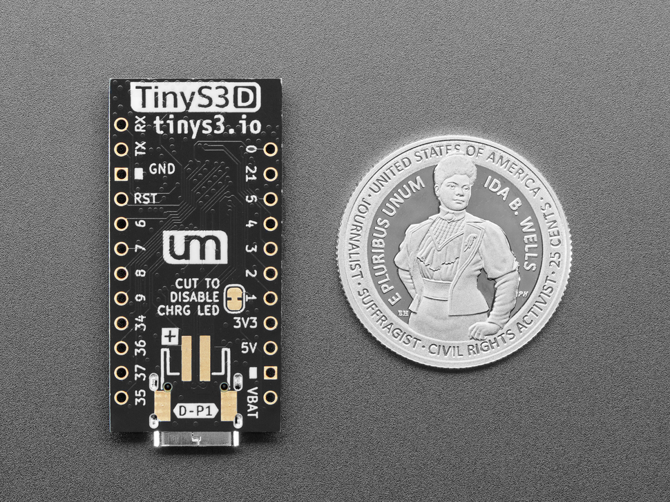 Back of small, black, rectangle-shaped microcontroller with U.S. quarter for scale.