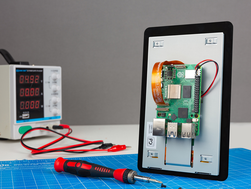 Lifestyle image of 5 inch touch screen with oscilloscope, screwdriver, and workspace.